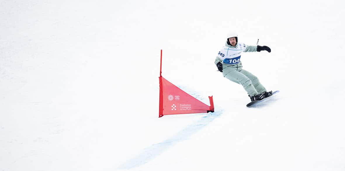 Snowboarder fährt um ein Tor im Schnee.