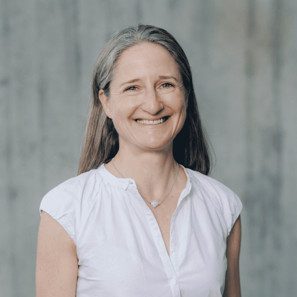 Lächelnde Frau mit grauem Haar und Bluse.