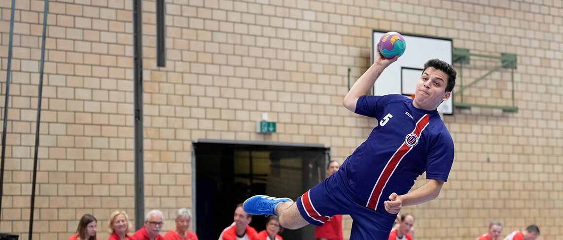 Handballspieler beim Sprungwurf in der Halle.
