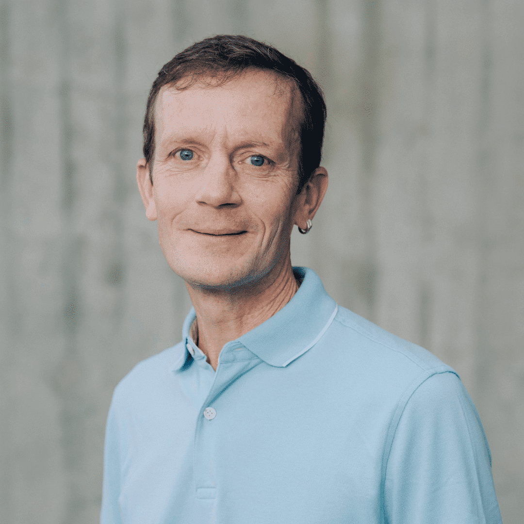 Mann mit blauem Polohemd lächelt freundlich.
