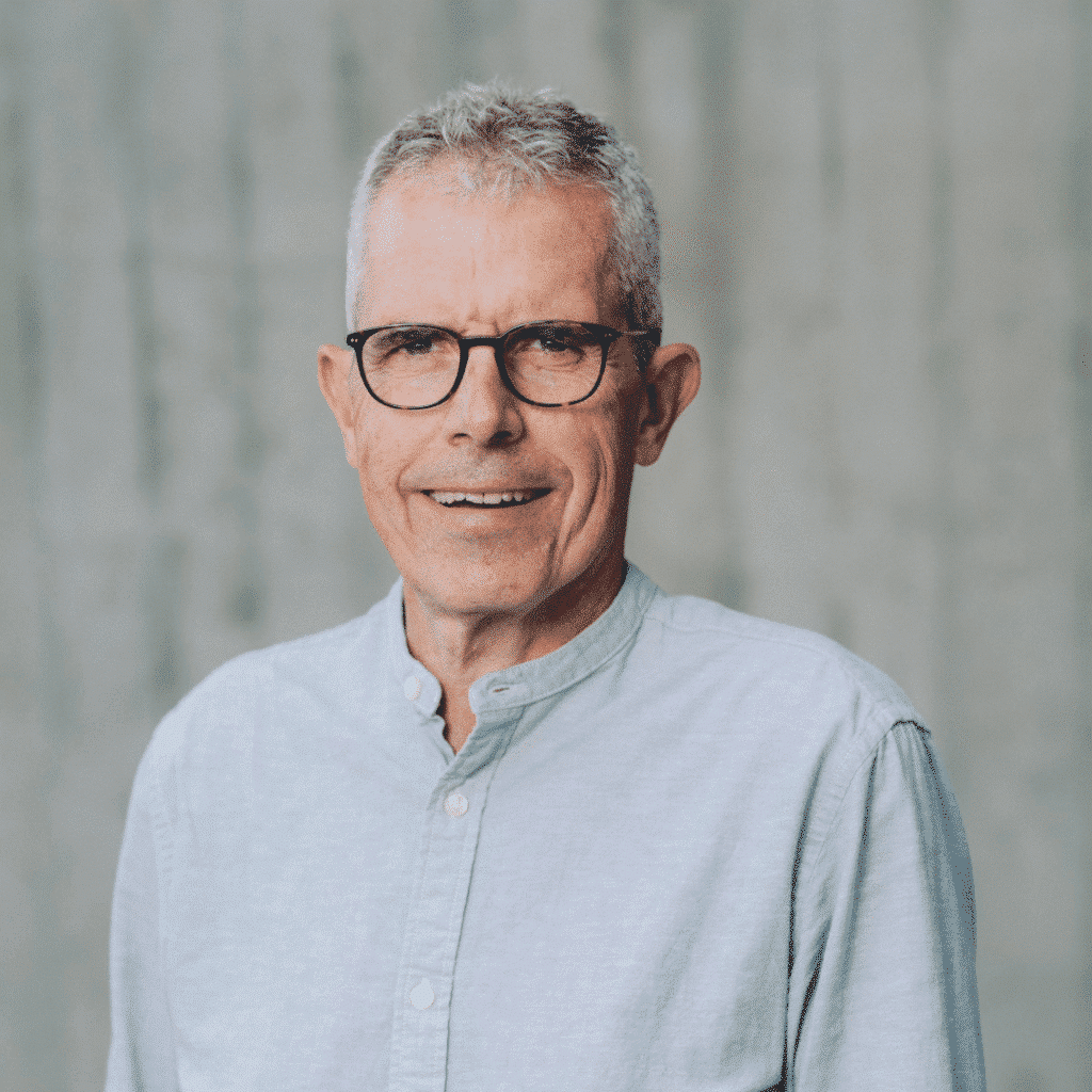Lächelnder Mann mit Brille und hellblauem Hemd.