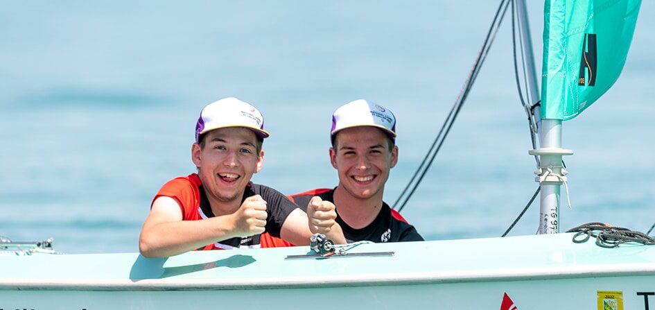 Zwei Jugendliche beim Segeln mit Daumen hoch