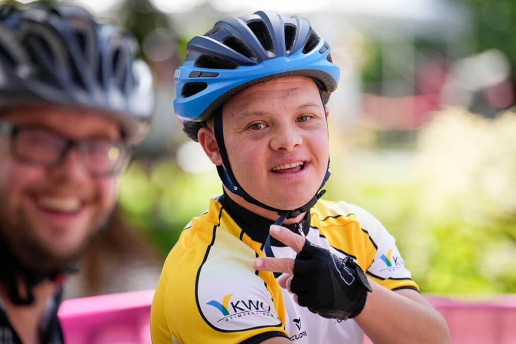 Junger Radfahrer mit Helm lächelt und posiert.