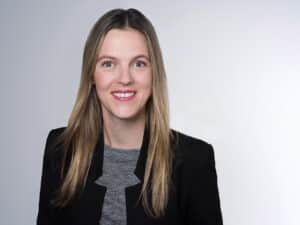 Lächelnde Frau mit blonden Haaren in schwarzer Jacke.