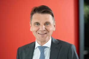 Mann mit Anzug vor rotem Hintergrund.