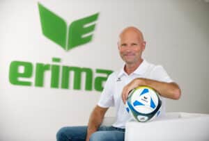 Man with soccer ball in front of Erima logo