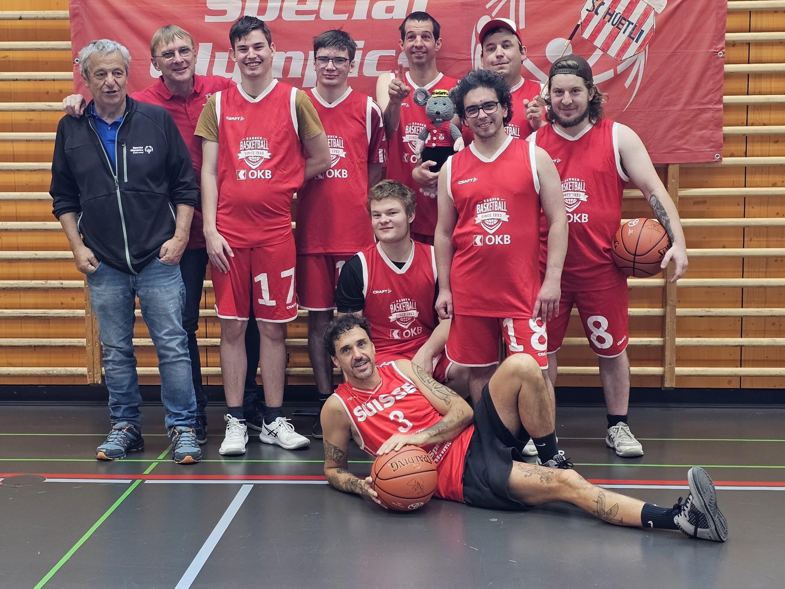 Squadra di Pallacanestro con giocatori e allenatori in abbigliamento sportivo.