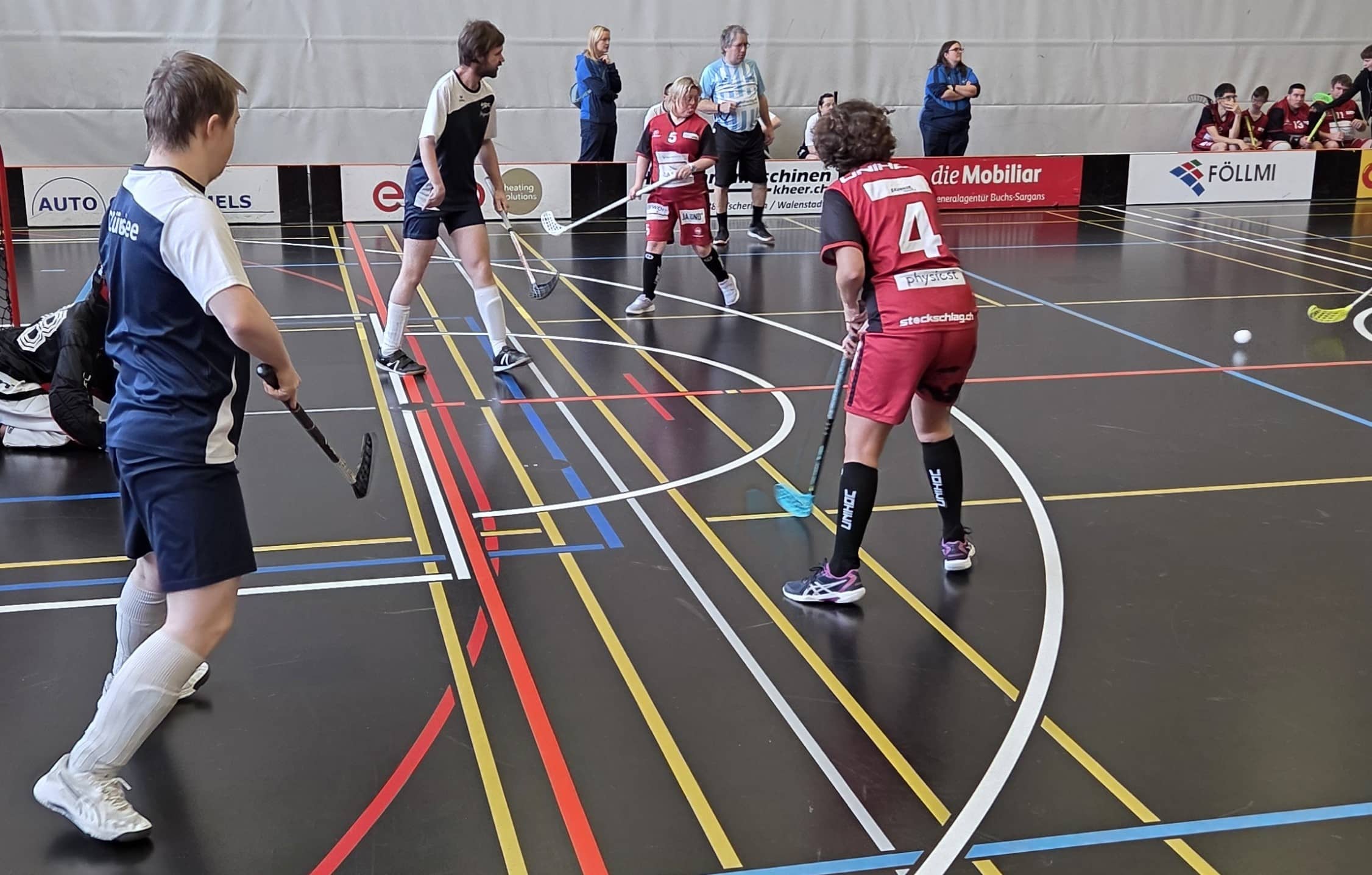 Jugendliche spielen Hallen-Hockey in einer Sporthalle.