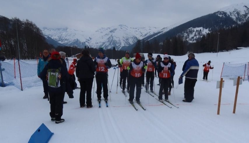 Langläufer warten am Start in verschneiter Landschaft.