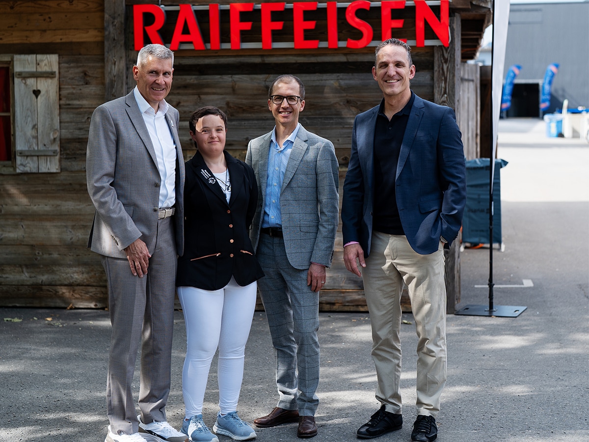Vier Personen vor Raiffeisen-Schriftzug im Freien