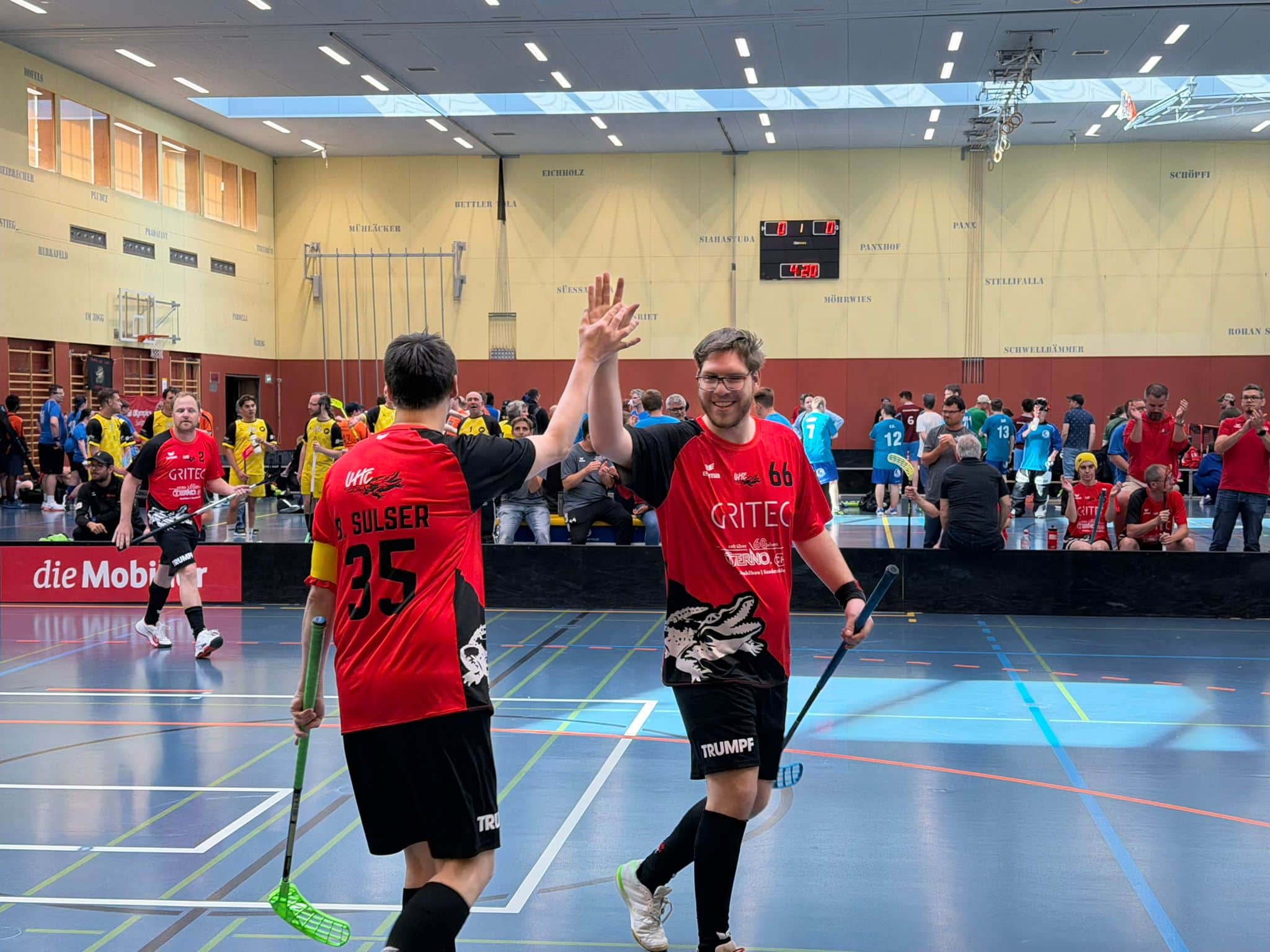 Zwei Unihockey-Spieler klatschen in Sporthalle ab